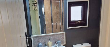 Een badkamer met een witte wastafel, een spiegel, een toilet en een klein raam.