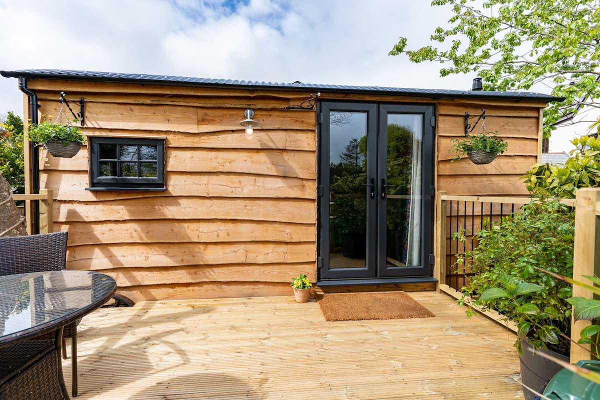 A wooden cabin with a glass door, a small window, and a patio with a table and chairs.