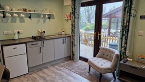 Une cuisine moderne dotée d’un four encastré, d’un évier et d’une fenêtre donnant sur une terrasse en bois.