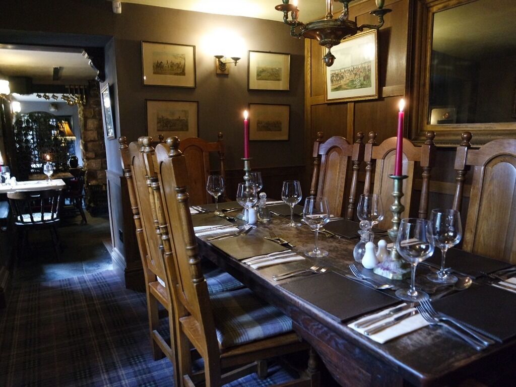 A dining area with a long wooden table set for a meal, flanked by chairs with cushioned seats.