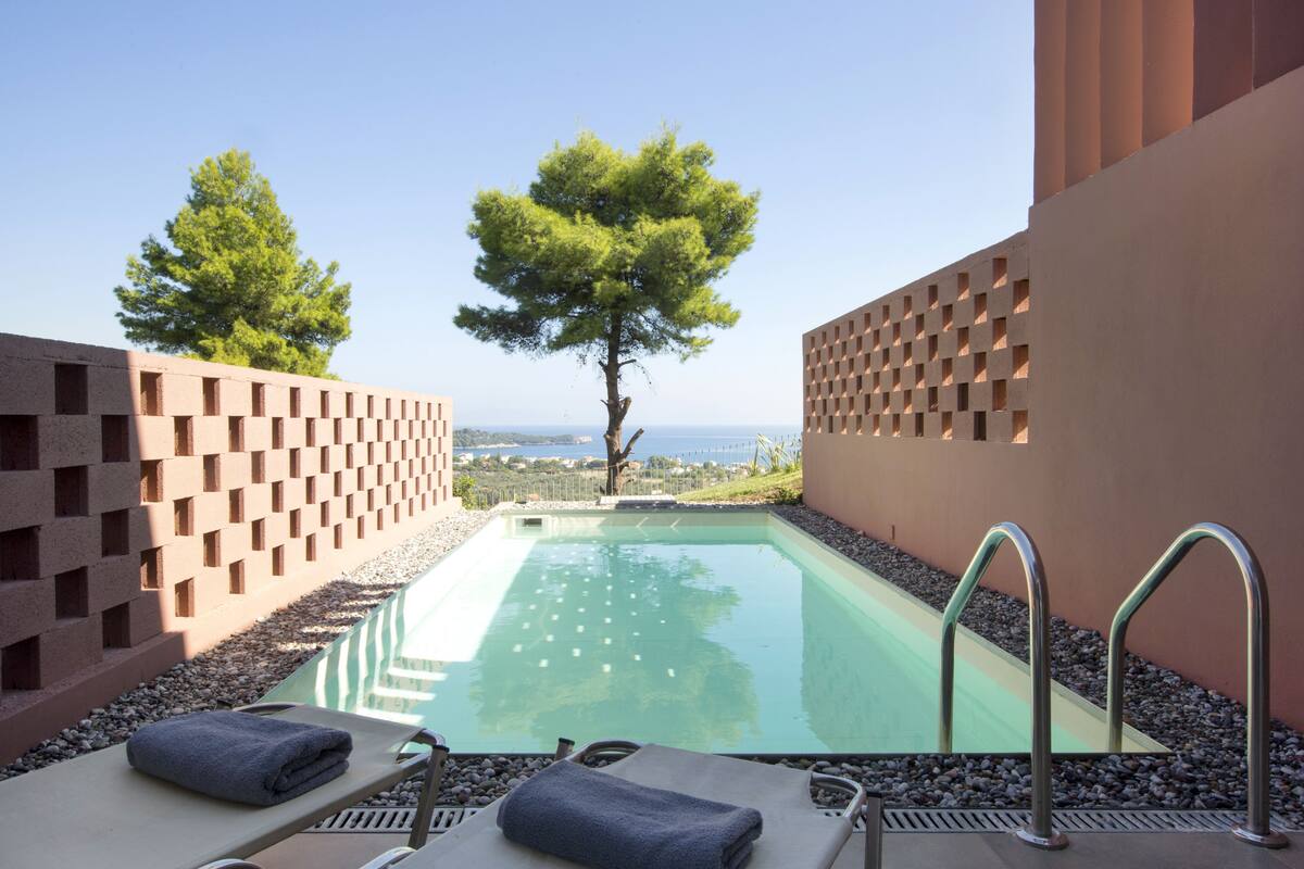 A pool area with lounge chairs and a view of the sea.