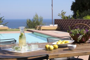 A poolside table with a pitcher of lemonade, glasses, lemons, and a basket of flowers. - Amandola Villas (Mantoudi-Limni-Agia Anna)