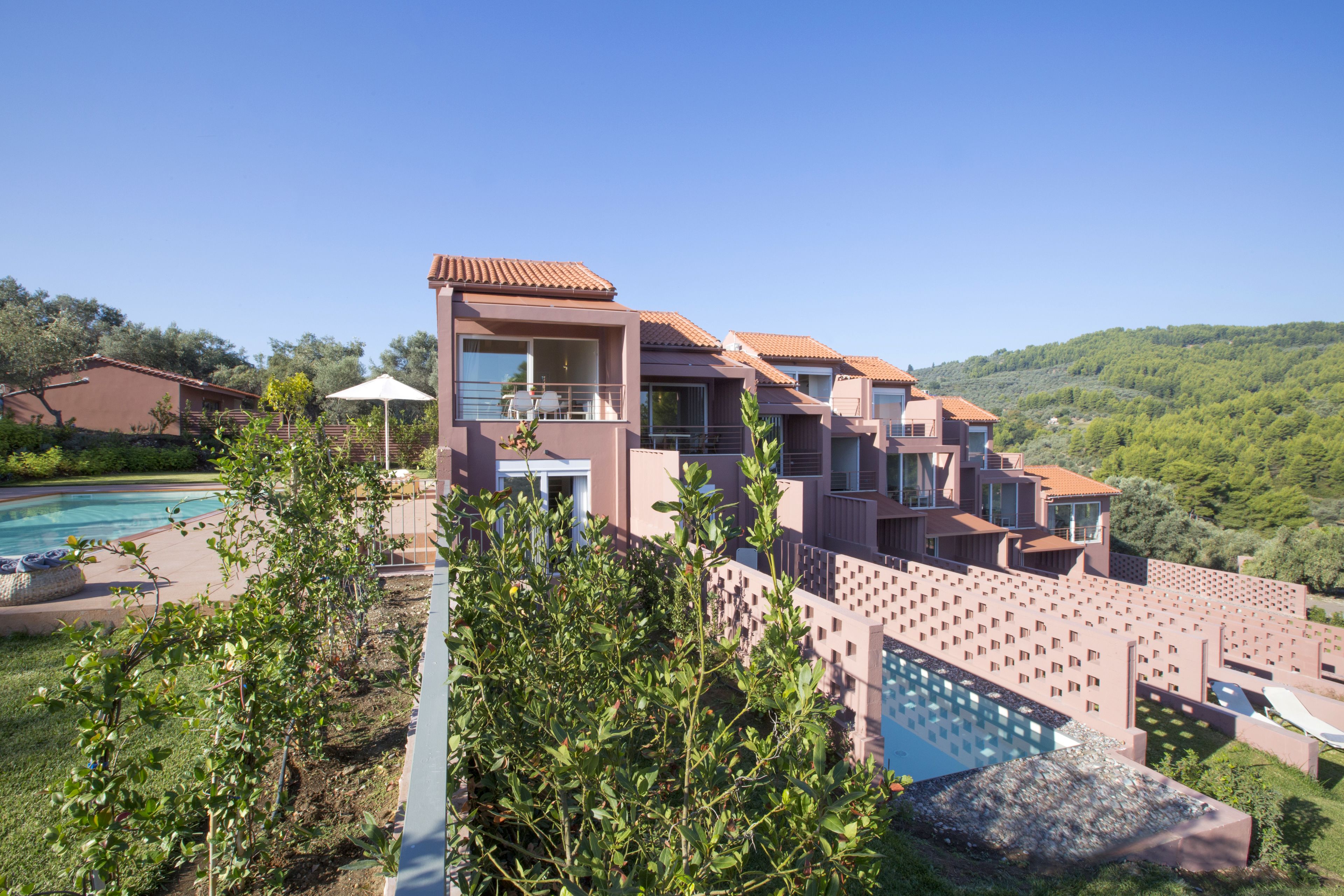 A modern multi-story house with a swimming pool, surrounded by lush greenery and hills.
