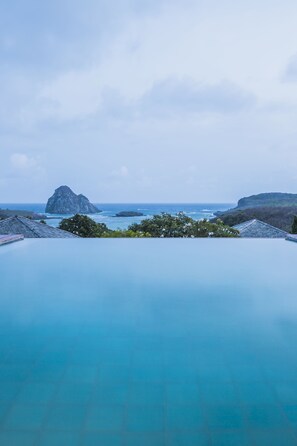 A infinity pool with a view of the ocean and a rocky island. - Pousada Maravilha Fernando de Noronha (Fernando de Noronha)