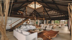 A spacious living area with a high ceiling, a central seating arrangement, and a staircase leading to an upper level. - Pousada Maravilha Fernando de Noronha (Fernando de Noronha)