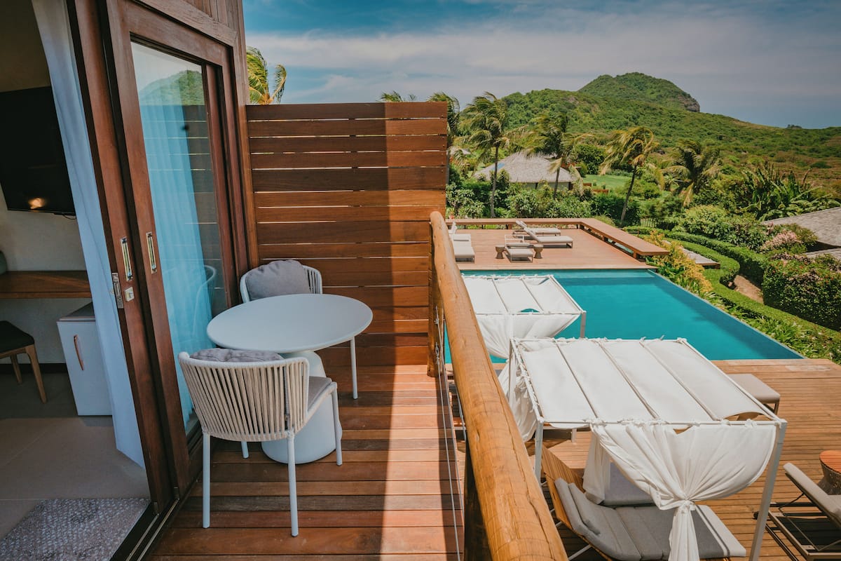 A wooden deck with a pool, lounge chairs, and a table.