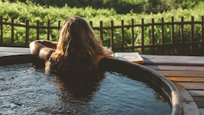 A person relaxing in a hot tub with a view of the ocean and greenery. - Pousada Maravilha Fernando de Noronha (Fernando de Noronha)