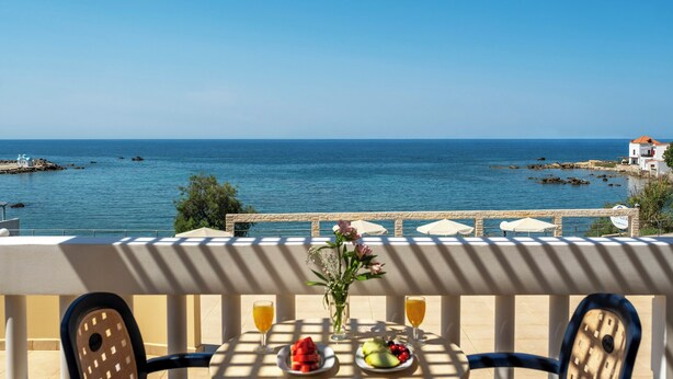 A table with a view of the sea, a flower vase, and fruit plates. - Porto Alegre (Chania)