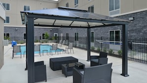 Un patio techado al aire libre con piscina, zona de estar y un edificio de piedra al fondo.