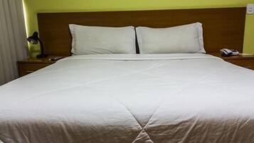 A neatly made bed with a wooden headboard, a bedside lamp, and a telephone on the nightstand.
