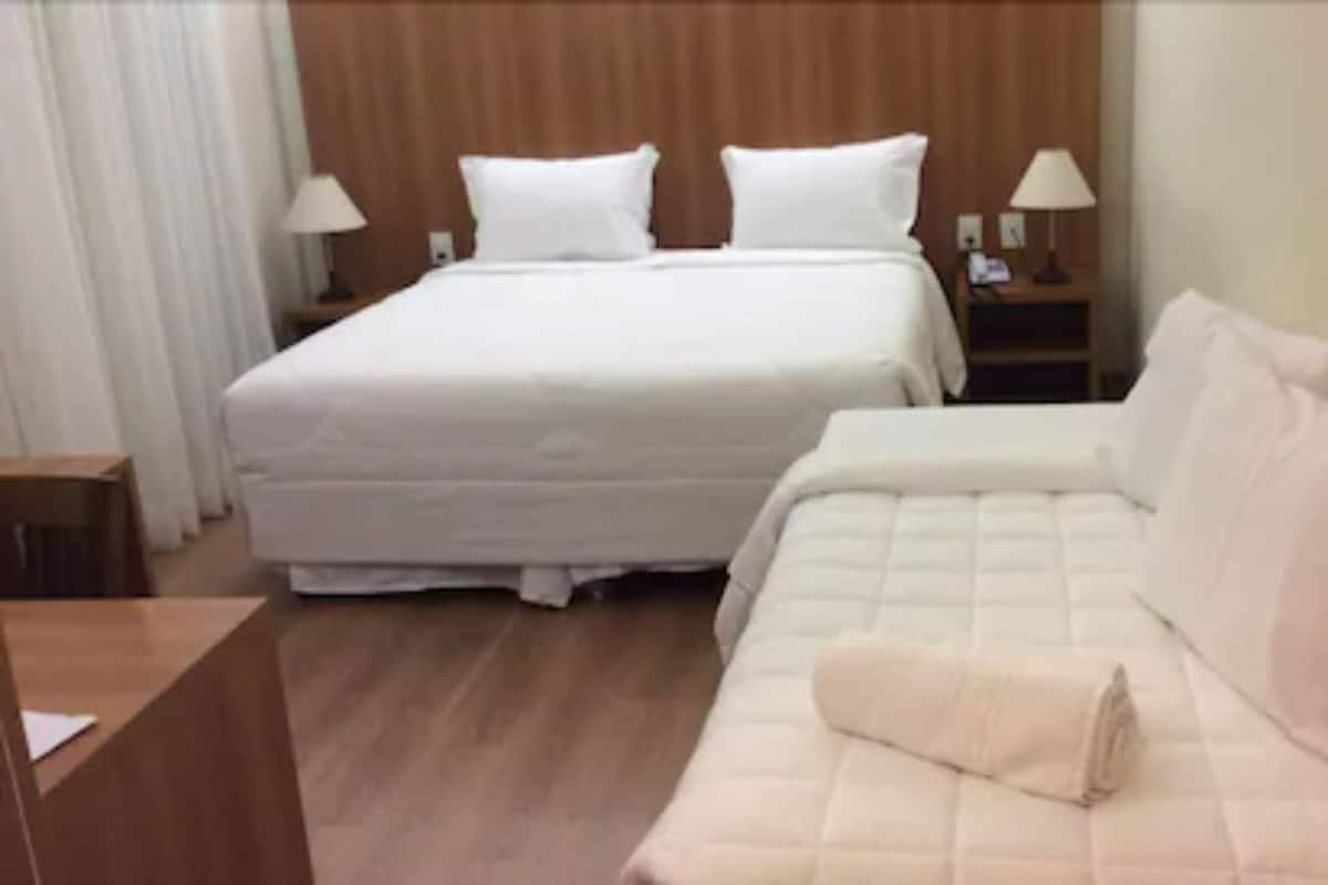 Une chambre d’hôtel avec deux lits, une tête de lit en bois, une table de chevet avec une lampe et une petite table avec une lampe.