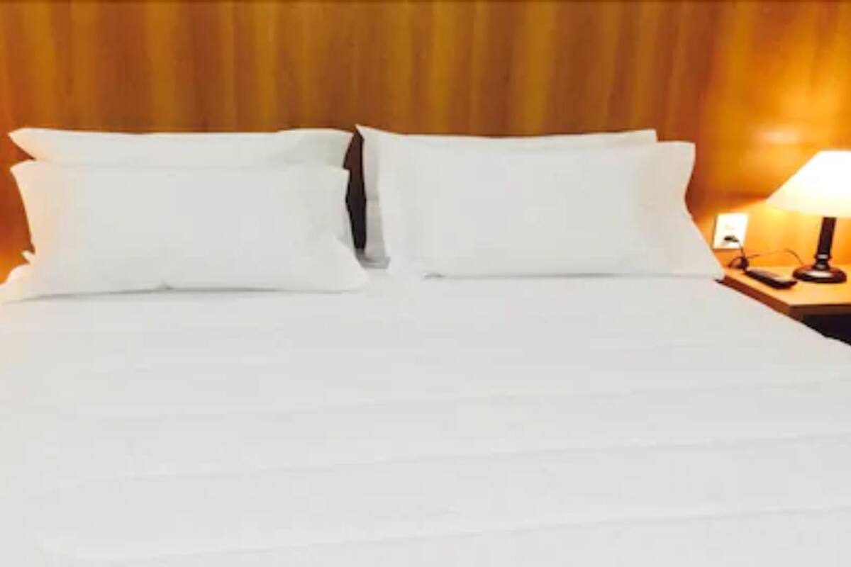 Un lit bien fait, avec du linge de lit blanc, dans une chambre d'hôtel.
