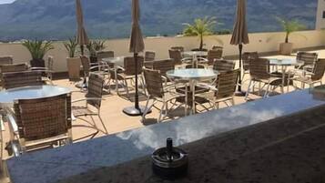 Un espacio al aire libre con mesas y sillas, rodeado de montañas.