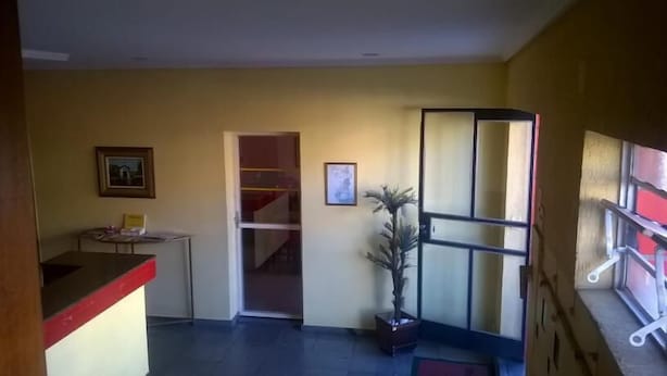 Un pasillo con un escritorio, un cuadro enmarcado, una planta en maceta y una escalera.