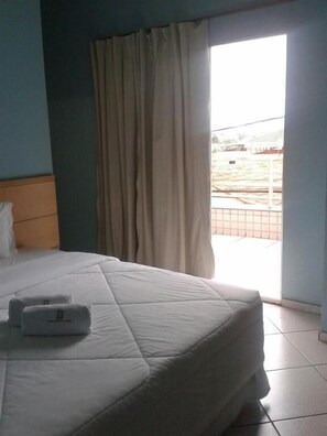 Une chambre d’hôtel avec un lit, un oreiller, une couverture et une fenêtre avec des rideaux.