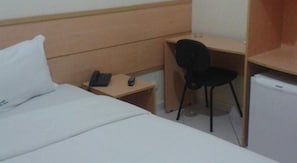 Une chambre d’hôtel équipée d’un lit, d’un bureau, d’une chaise, d’un téléphone et d’un réfrigérateur.