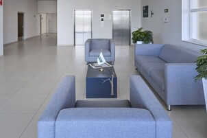 Um hall moderno com um sofá azul, uma poltrona a combinar e uma mesa de centro com um jornal e uma bandeira.