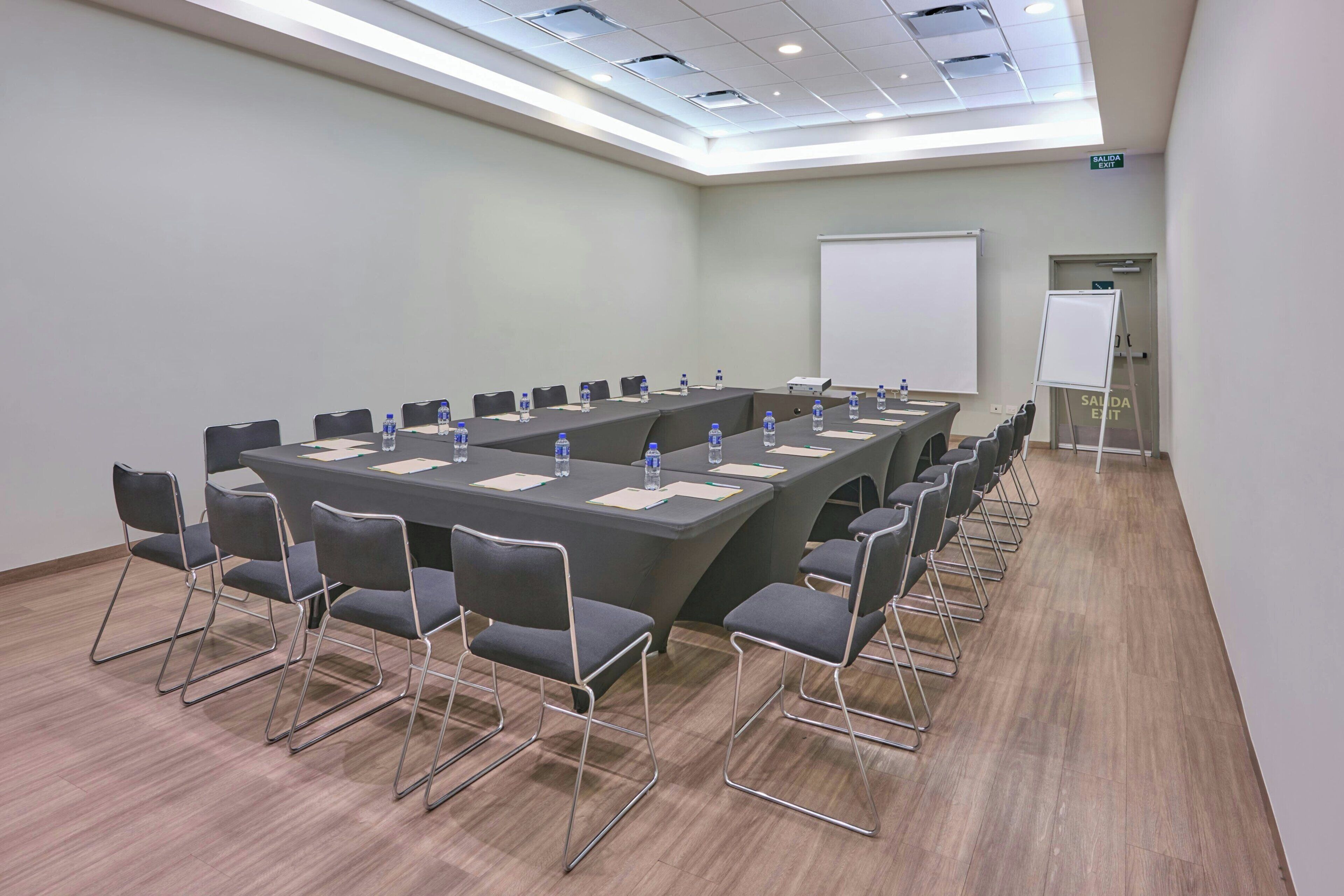 A conference room with a long table, chairs, water bottles, and a whiteboard.