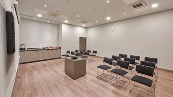 Une salle de conférence avec une longue table et des chaises, un coin cuisine et une porte.