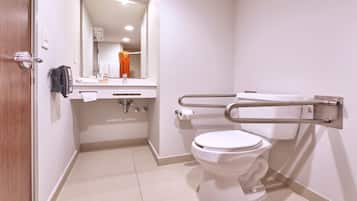 A modern bathroom with a toilet, hand dryer, and a towel rack.
