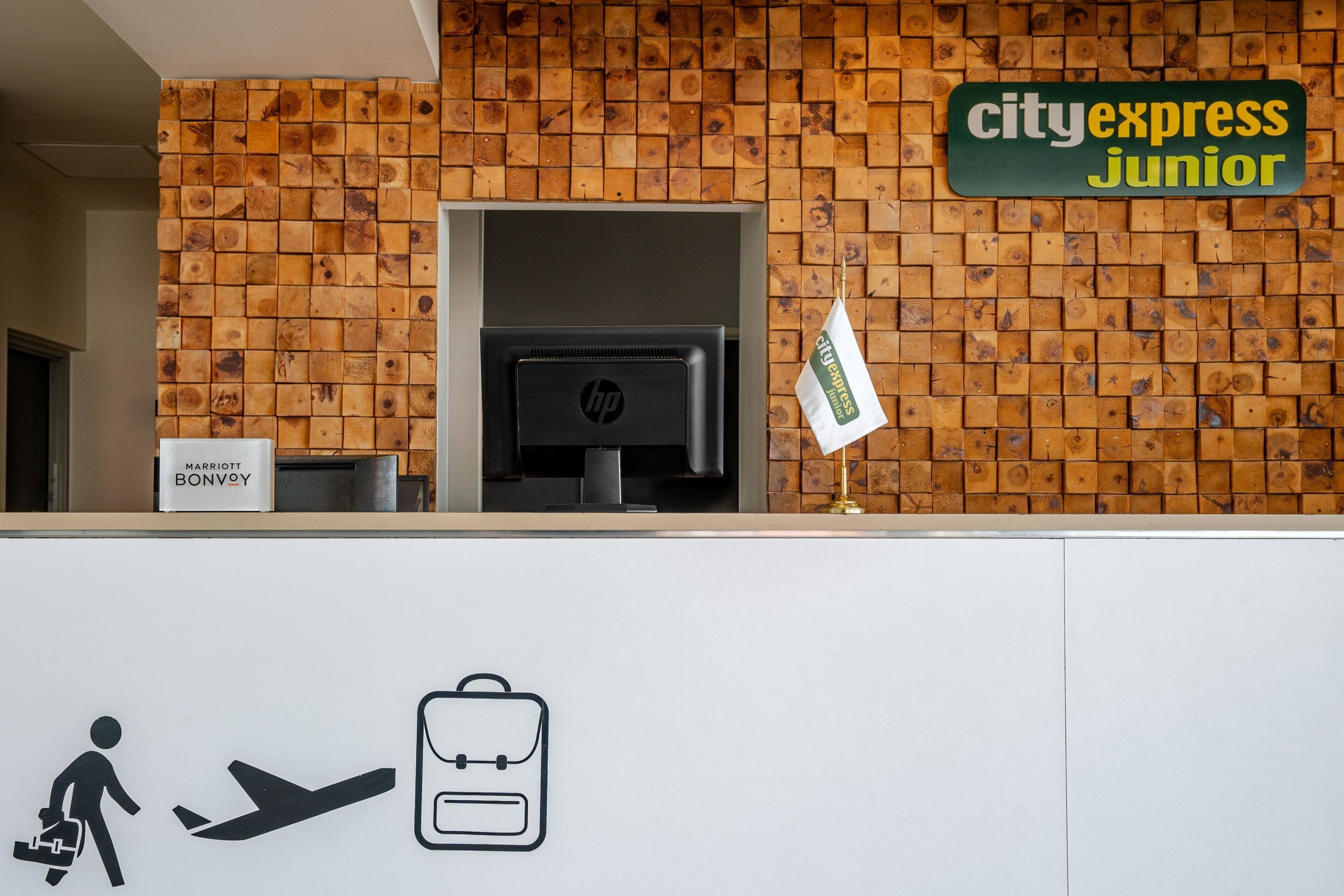 Ein Empfangsschalter mit einer Holzwand, ein Schild für CityExpress Junior und ein Schild für Marriott Bonvoy.