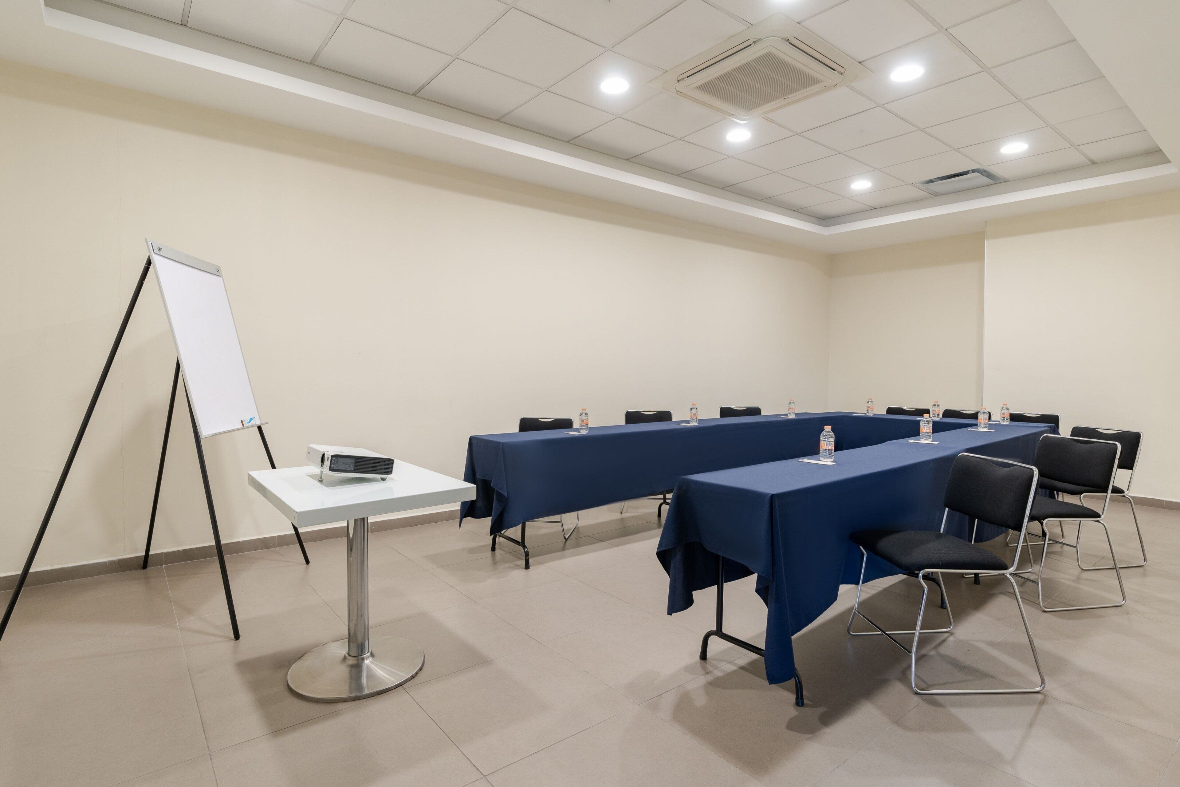 A conference room with a long table, chairs, a whiteboard, and a projector.