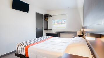 A modern hotel room with a bed, bedside table, and a flat-screen TV mounted on the wall.