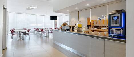 A modern hotel lobby with a long reception desk, seating area, and a large window providing natural light.