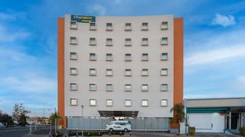 Et CityExpress Junior hotel med en moderne facade, flere vinduer og en parkeringsplads med en hvid varevogn.