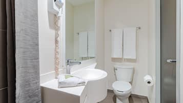 Un baño moderno con lavamanos, espejo e inodoro blancos.