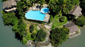 An aerial view of a resort with a swimming pool surrounded by palm trees and a small dock. - Santa Clara Hotel (Paraty)