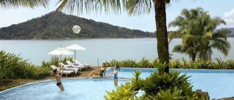 Een buitenzwembad, parasols voor strand/zwembad