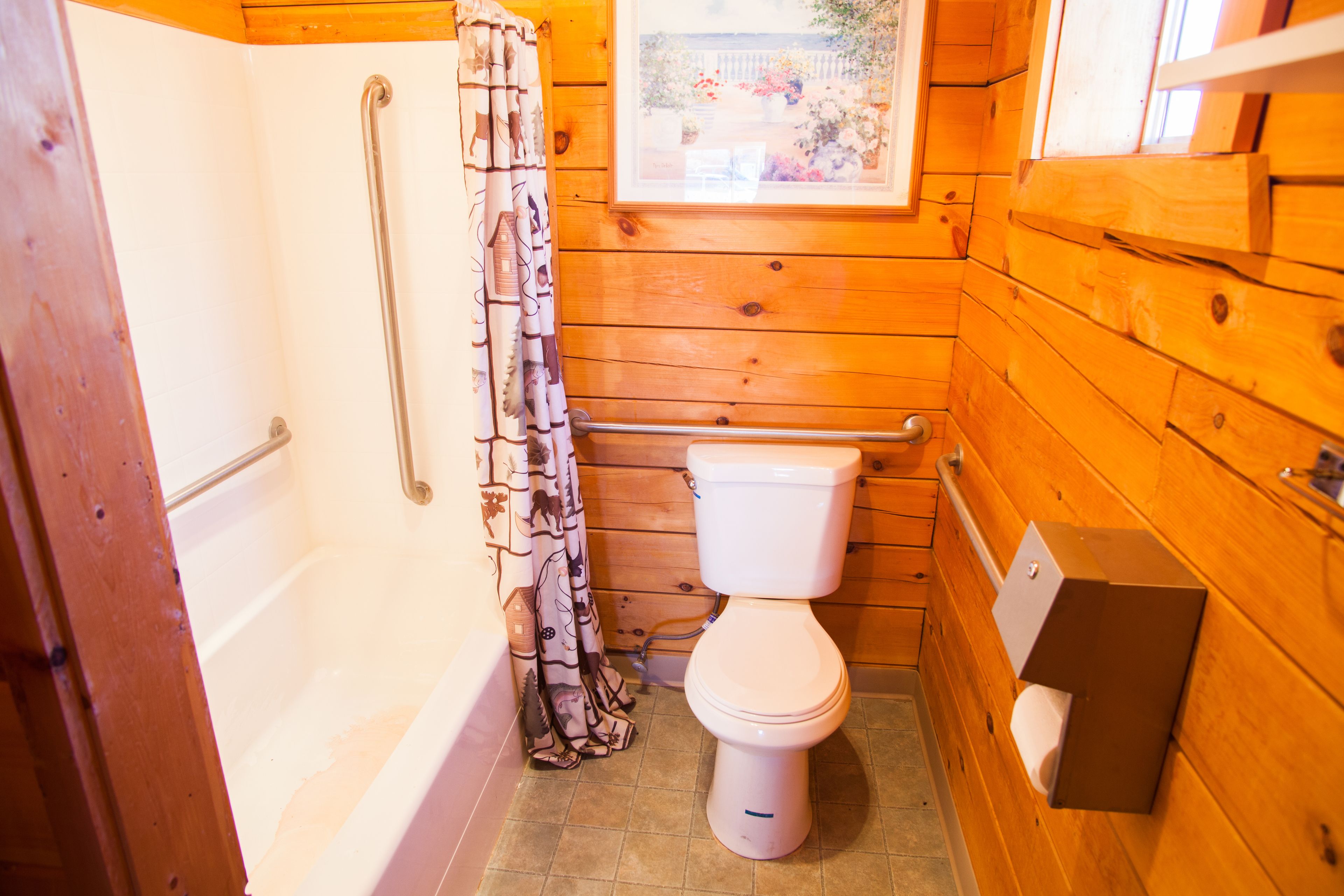 A wooden bathroom with a bathtub, toilet, and a shower with a handrail.