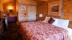 Une chambre dans un chalet en bois, comprenant un lit, une salle de bain et un bureau.