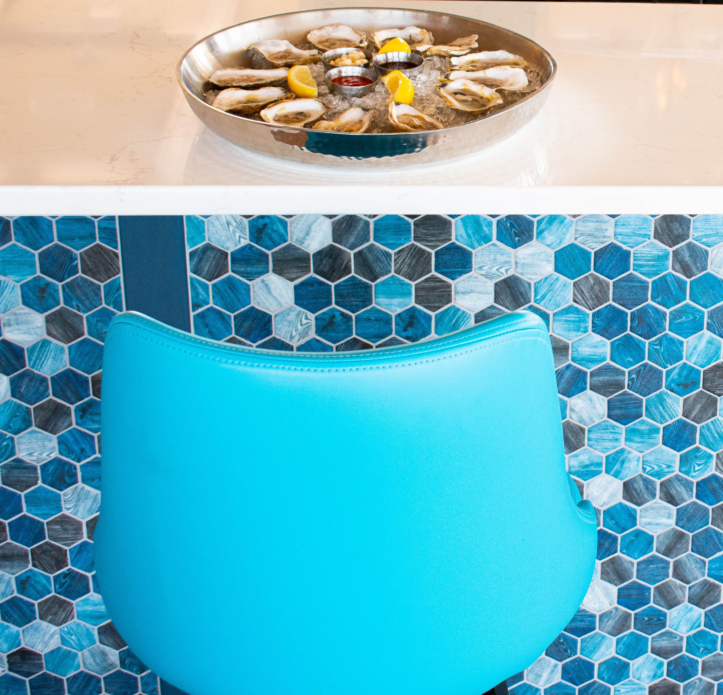 Una silla azul con un patrón de baldosas hexagonales al fondo.