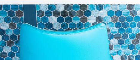 Una silla azul con un patrón de baldosas hexagonales al fondo.
