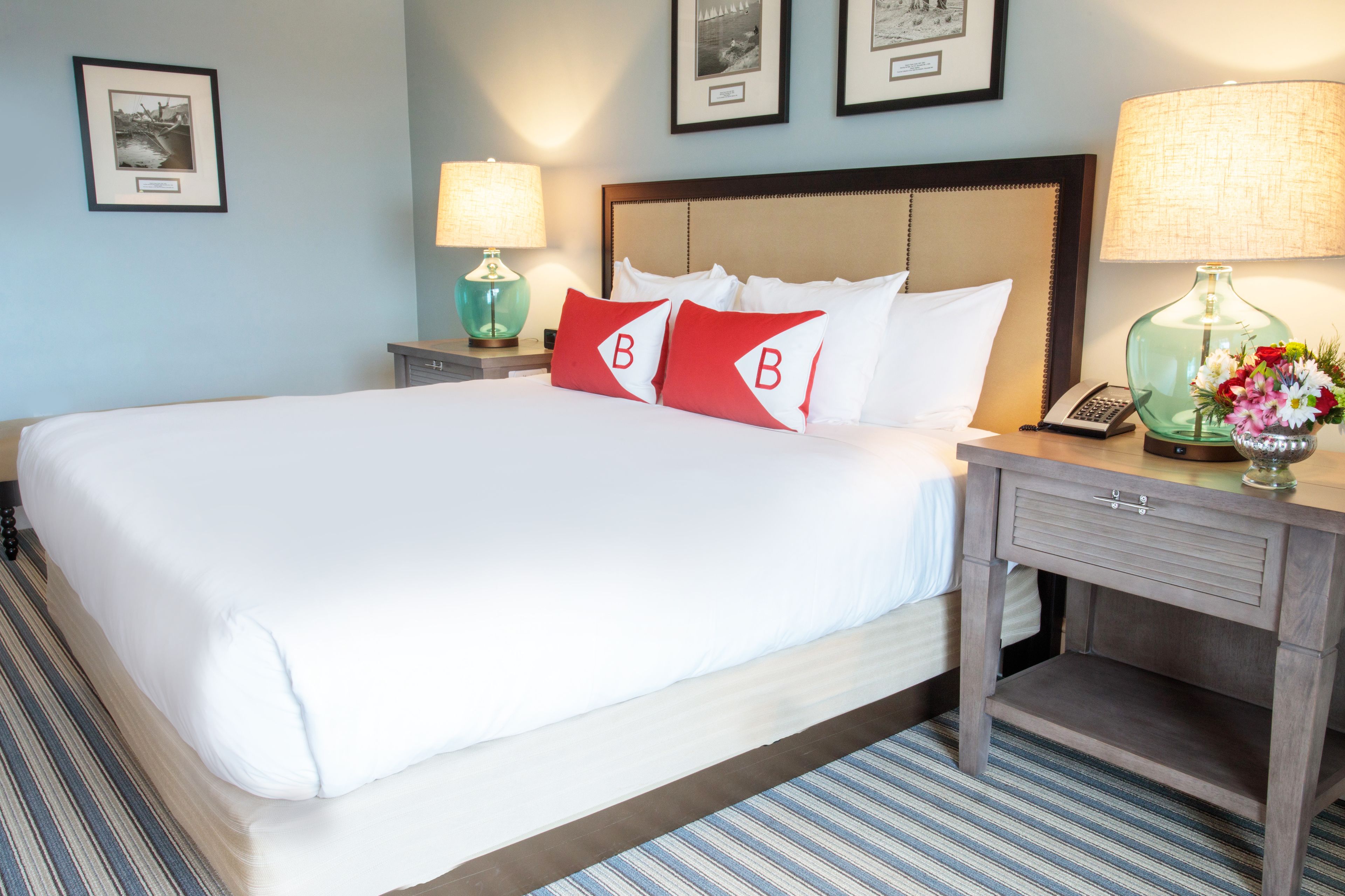 A hotel room with a large bed, two bedside tables, a nightstand, and a lamp.