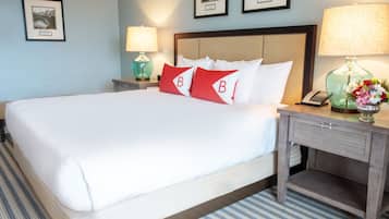 A hotel room with a large bed, two bedside tables, a nightstand, and a lamp.