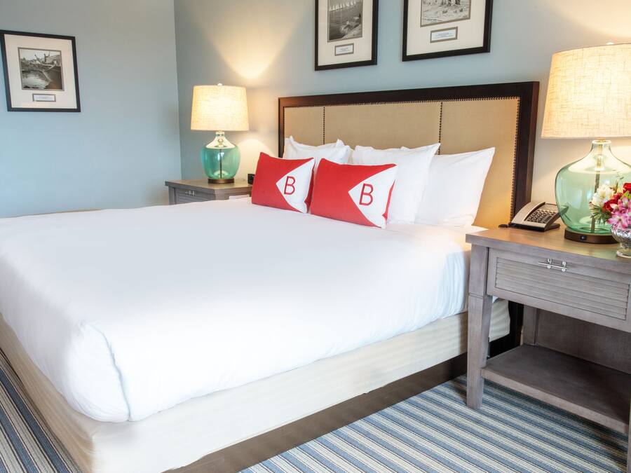 A hotel room with a large bed, two bedside tables, a nightstand, and a lamp.