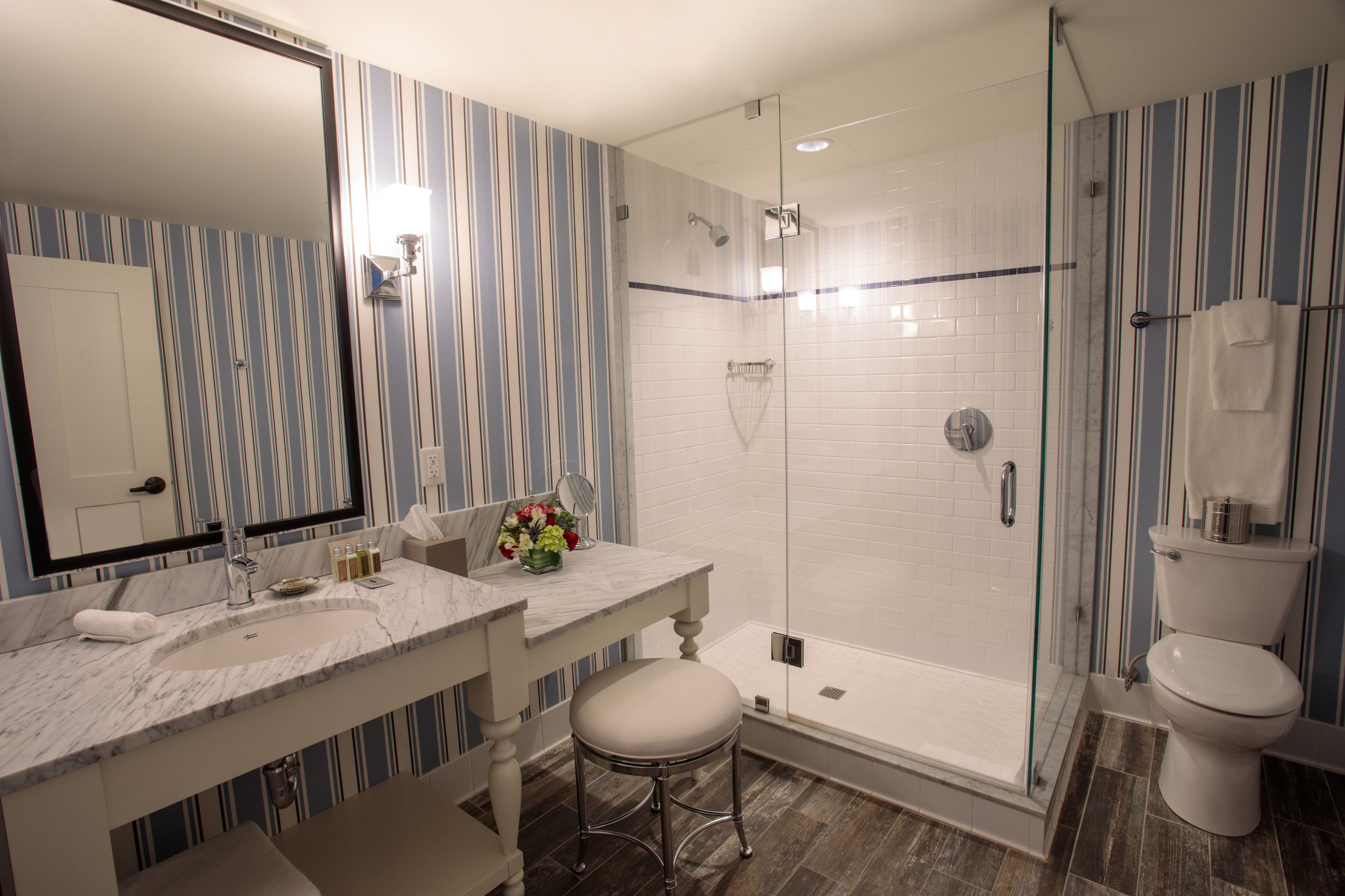 Un baño con cabina de ducha de vidrio, un lavabo blanco y un espejo.