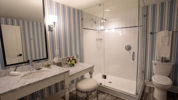 Un baño con cabina de ducha de vidrio, un lavabo blanco y un espejo.