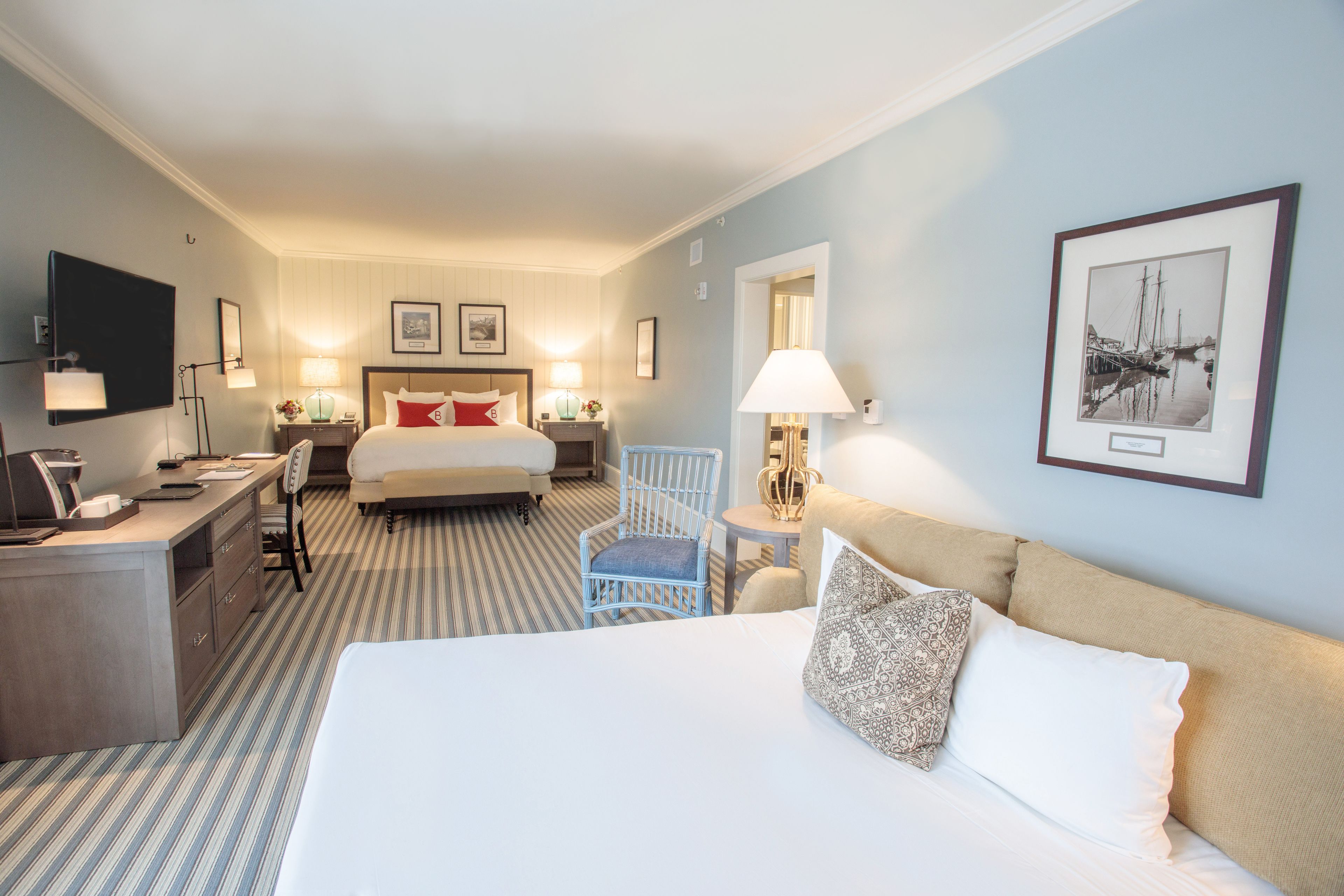 Une chambre d’hôtel avec un grand lit, un bureau, une chaise, une petite table et un téléviseur.