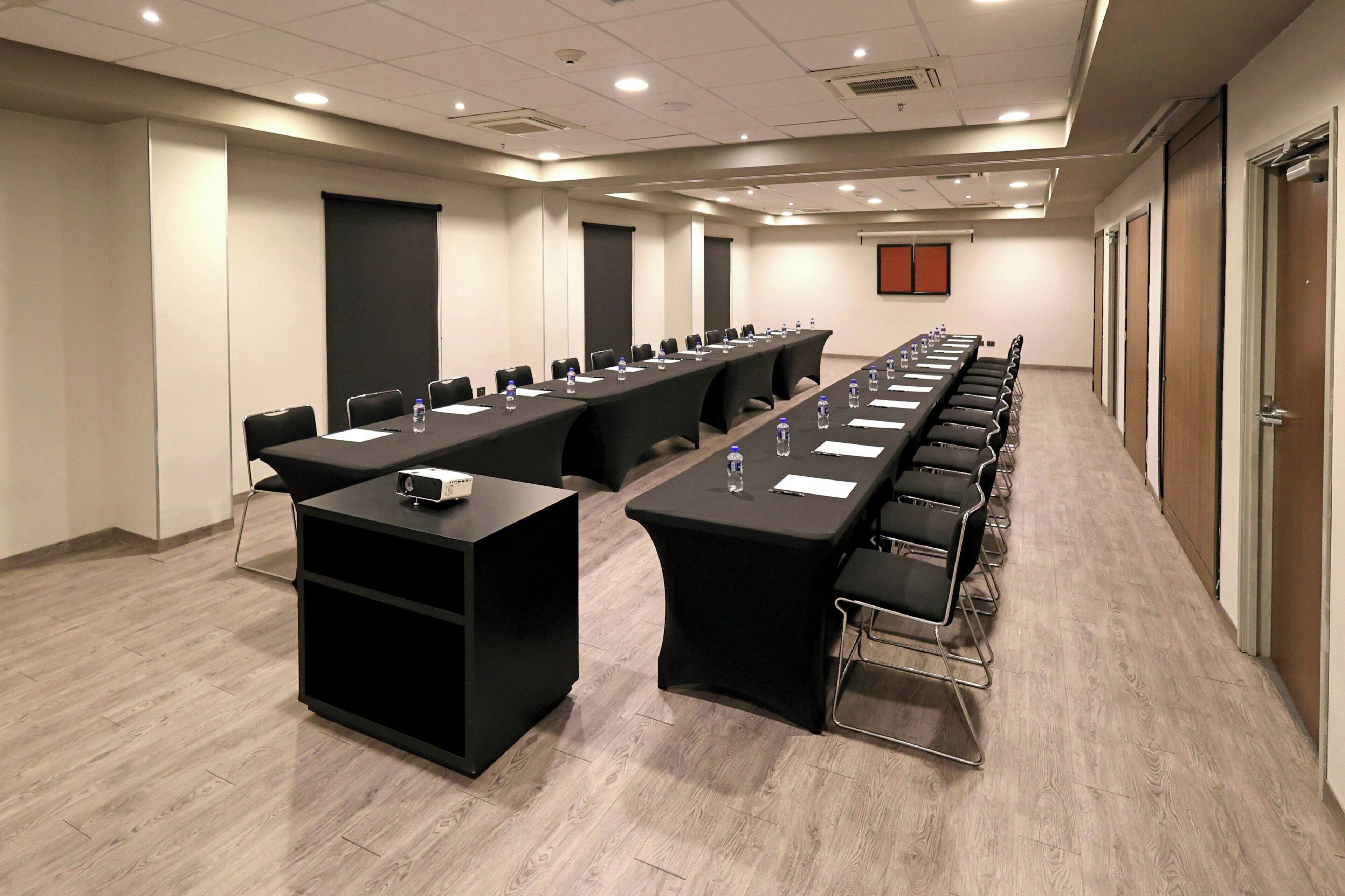 A conference room with a long table, chairs, a projector, and a screen.