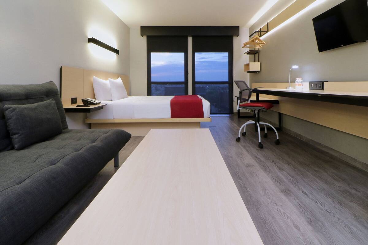 Een moderne hotelkamer met een bed, bureau, stoel en een bank.