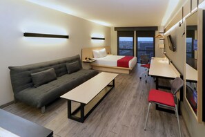 A modern hotel room with a sofa, bed, desk, and chair. - City Express by Marriott Piedras Negras (Piedras Negras)