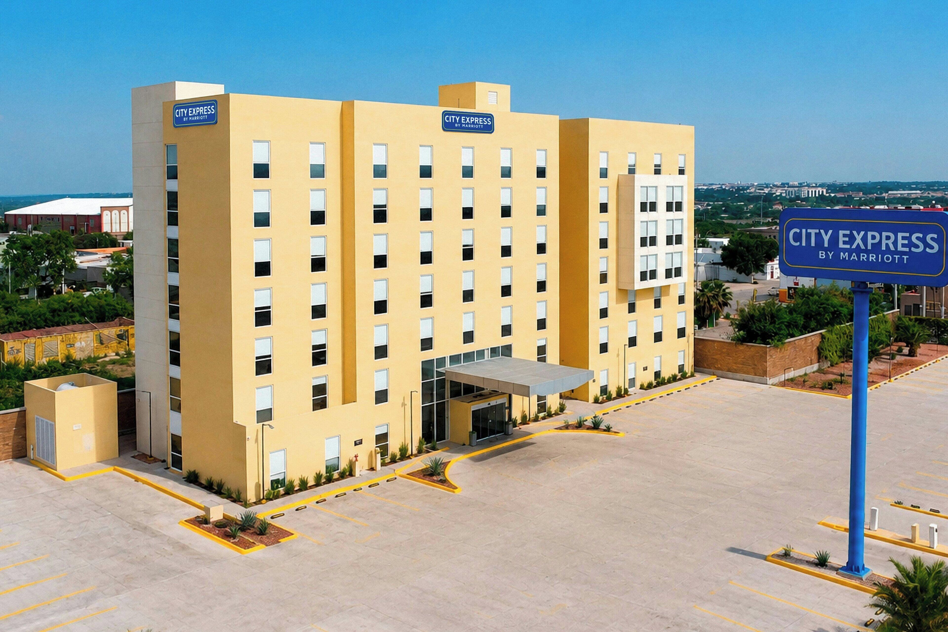 Um hotel com vários andares, fachada plana, entrada coberta e estacionamento.