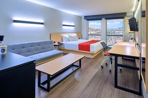 Una habitación de hotel con cama, sofá, escritorio y vistas a la ciudad.