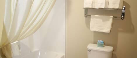 Une salle de bain avec une baignoire, des toilettes et une étagère avec des serviettes.