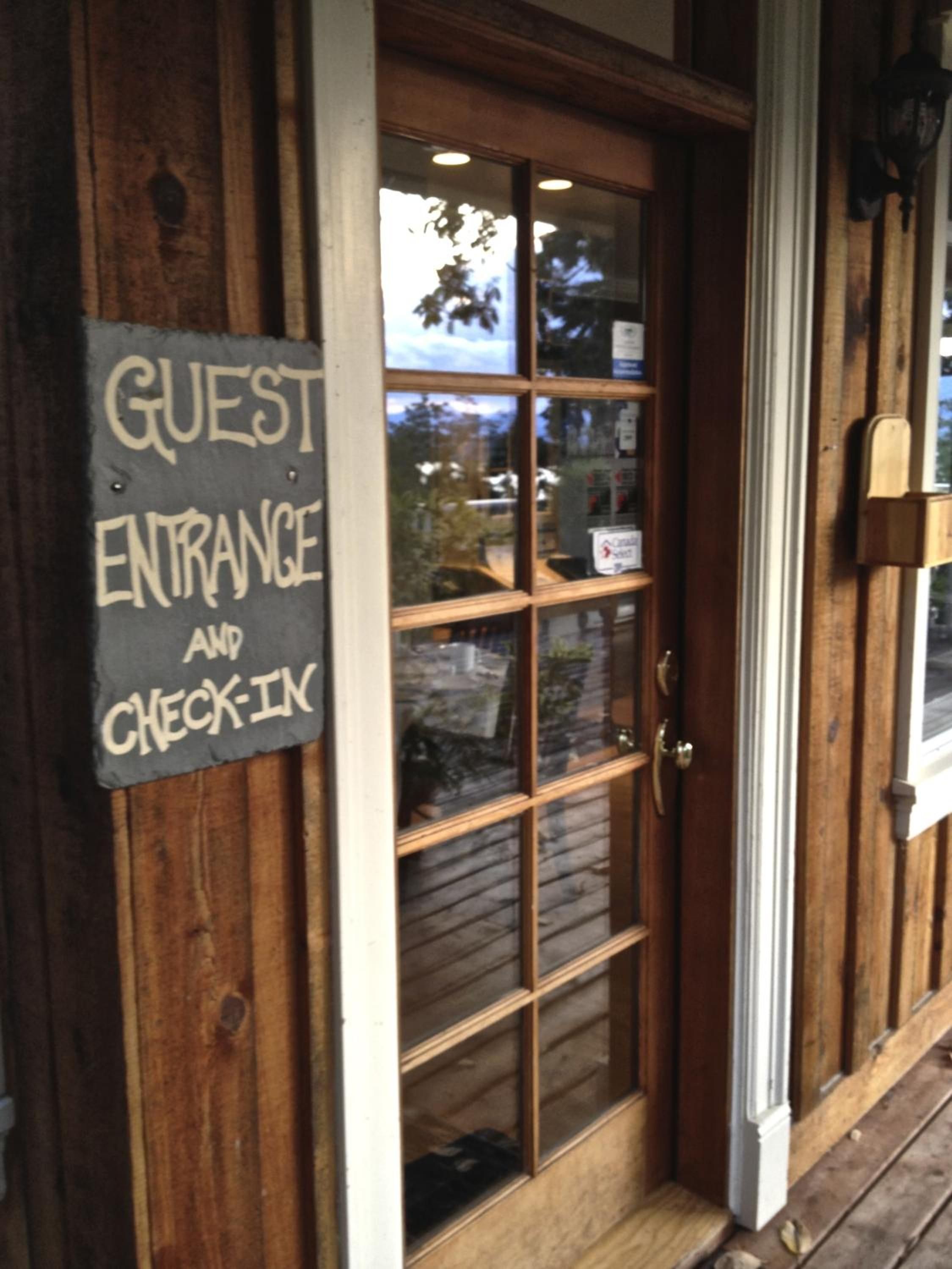 Une porte en bois avec une pancarte indiquant l’entrée réservée aux clients et le comptoir d’enregistrement.