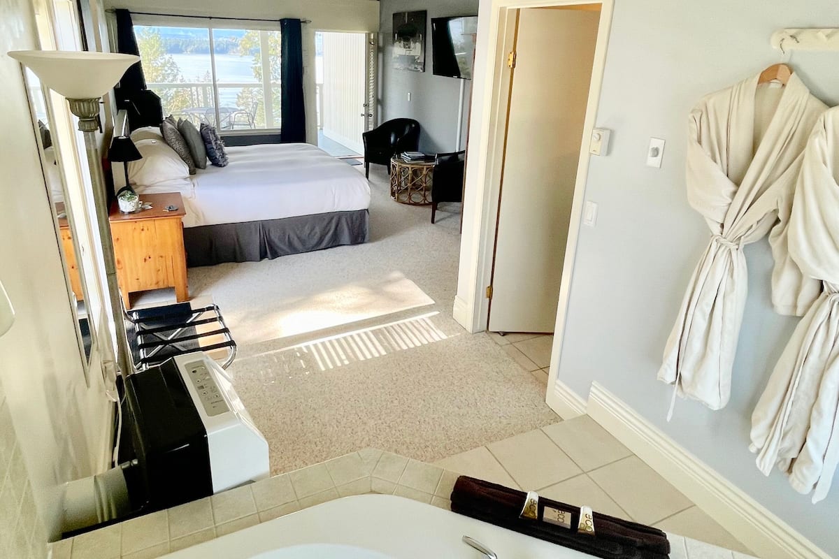 Ein Hotelzimmer mit Bett, Schreibtisch, Stuhl, Fernseher und einem Badezimmer mit Badewanne und Handtuchhalter.